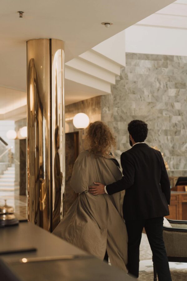 A couple walking in a luxurious hotel lobby, showcasing elegance and sophistication.