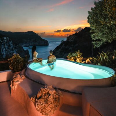 Couple enjoying a luxury resort pool with stunning sunset views in Ibiza.