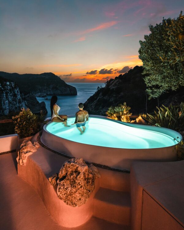 Couple enjoying a luxury resort pool with stunning sunset views in Ibiza.