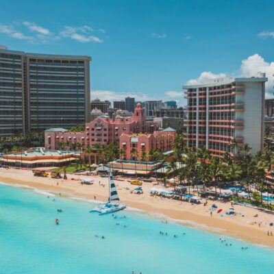 Stunning tropical beachfront resort with pink buildings and turquoise sea viewed from above.