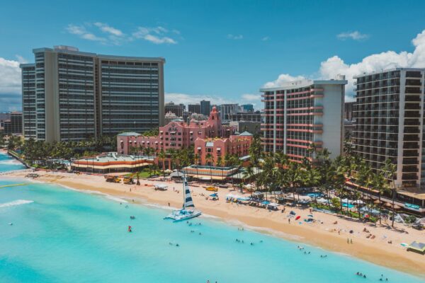 Stunning tropical beachfront resort with pink buildings and turquoise sea viewed from above.